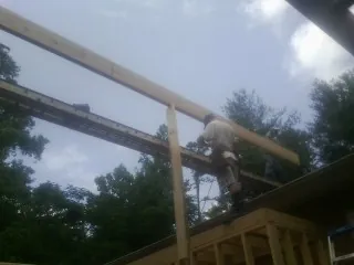 Carpenter setting a ridge beam over a new addition frame — Ice Dam Removal by Roofing Brothers in Mullens