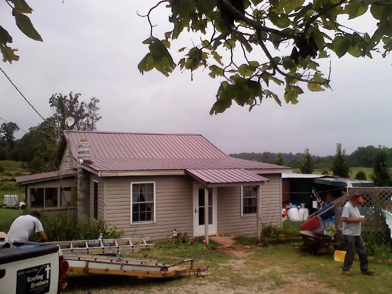 Crew finishing a mauve metal roof on a small farmhouse in Mullens