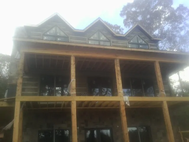Dormers and porch framing on a large log home under construction — Roof Coating work by our crew in Mullens