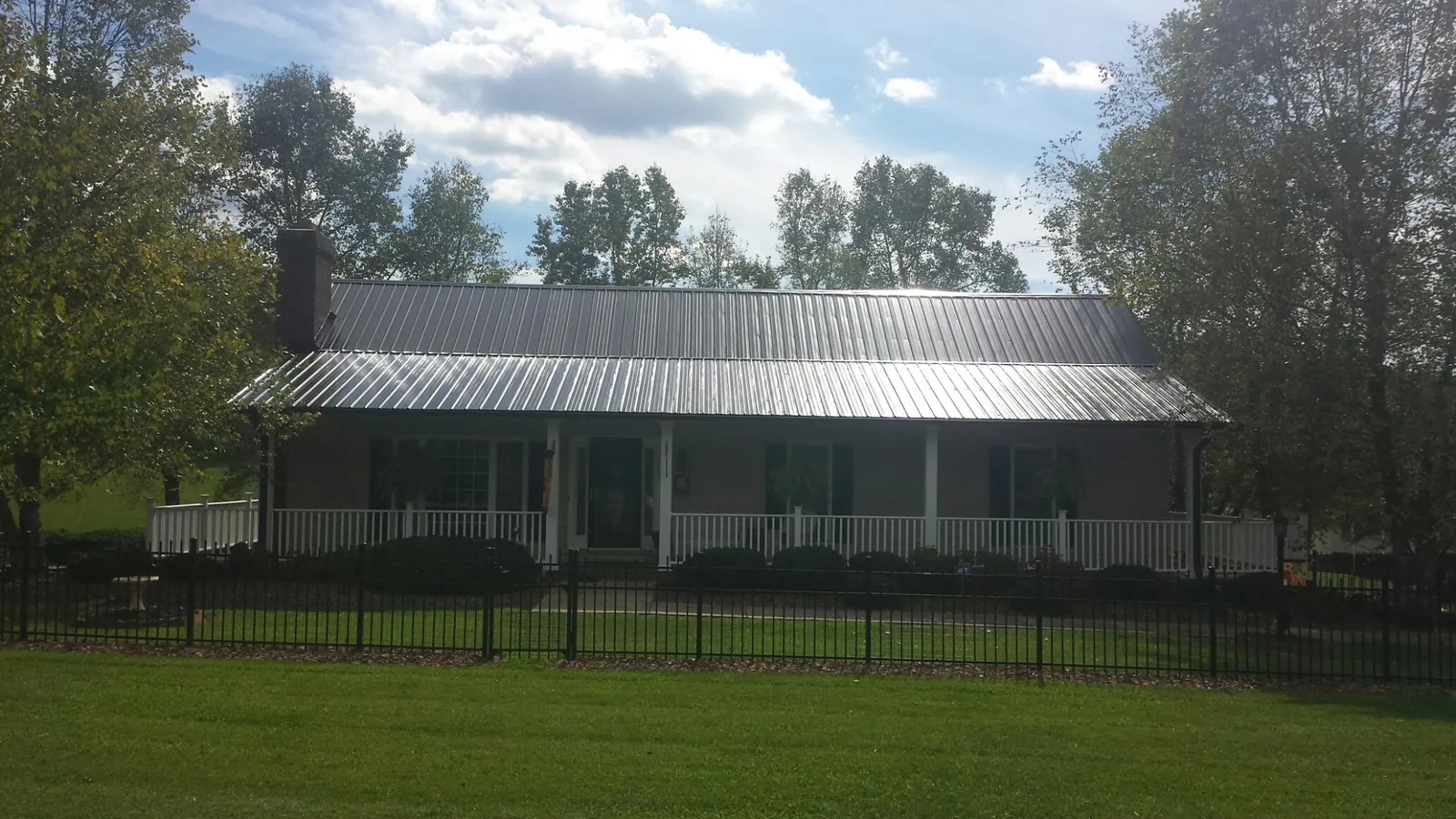 Gray metal roof on a brick ranch with a full width front porch — Gutter Guard Installation work by our crew in Mullens