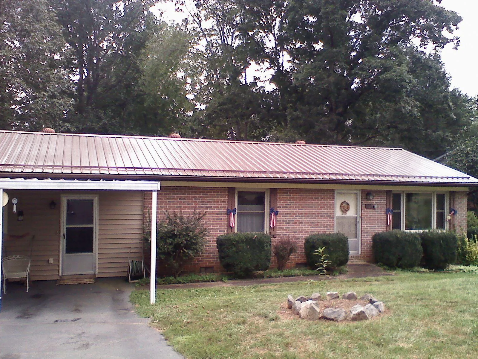 Bronze metal roof and carport on a brick ranch home — Roof Repair work by our crew in Mullens