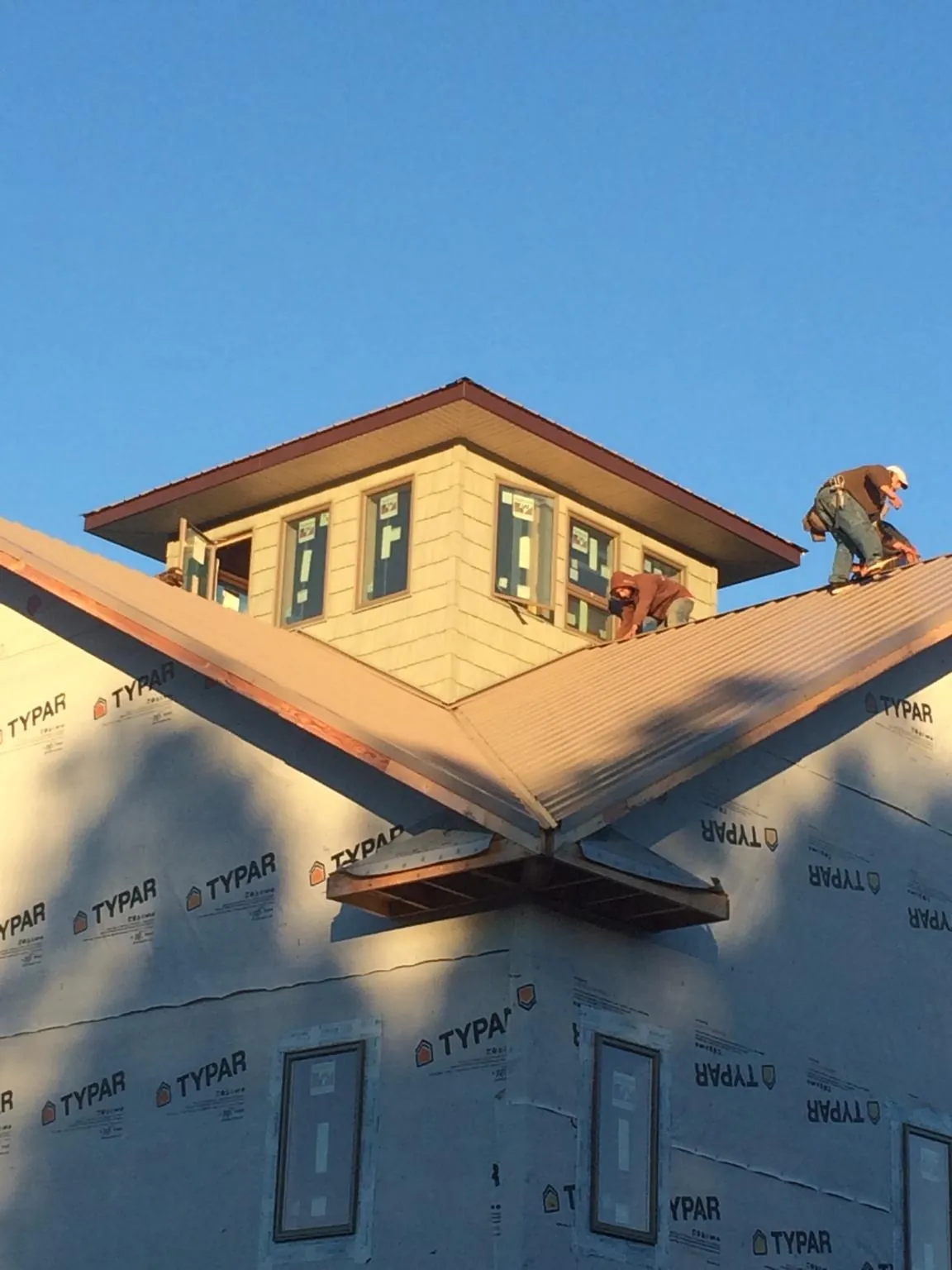 Roofers working around a rooftop cupola on a new metal roof at sunset — Roof Waterproofing in Mullens by Roofing Brothers